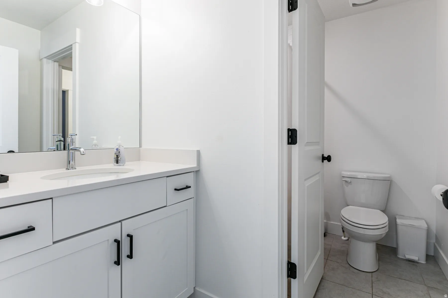 Modern vanity featuring a polished chrome faucet, under-mount sink, and quartz countertop