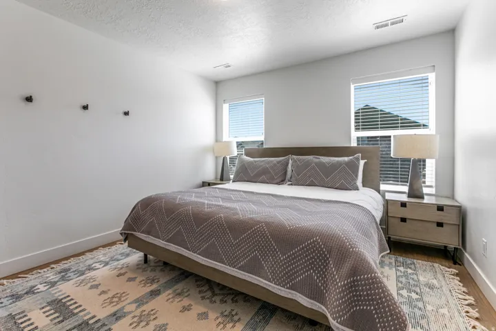 Bedroom featuring two windows with blinds, light-colored walls, wood-finish flooring, and recessed ceiling lighting