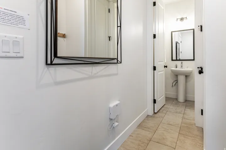 Pedestal sink with black-framed mirror, brushed nickel faucet, and coordinating light fixture