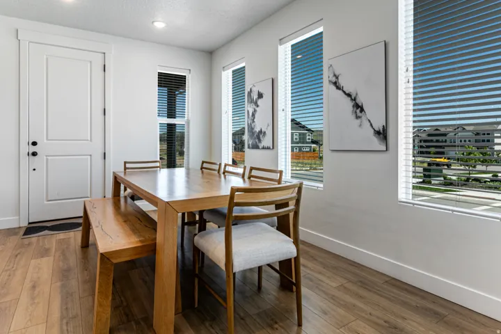 Naturally lit dining area featuring wood-finish flooring, recessed lighting, and multiple vertical windows with blinds