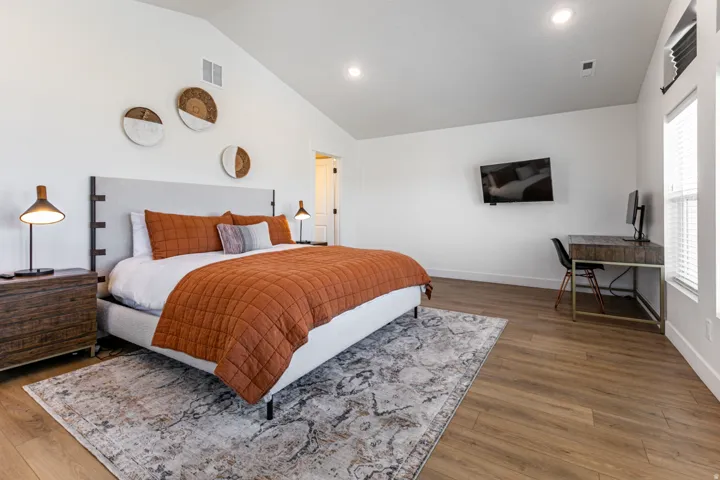 Spacious room featuring vaulted ceilings, wood-finish flooring, recessed lighting, and ample natural light from multiple windows