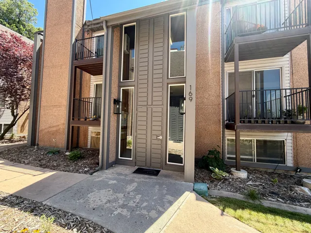 Modern facade of outside entry featuring a prominent entry door with vertical window panels and exterior sconce lighting