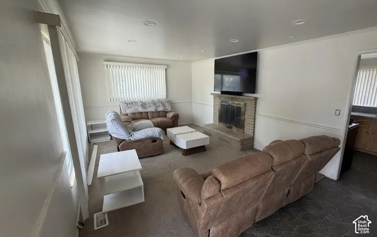 Spacious living area featuring a brick fireplace with a hearth, recessed lighting, crown molding, and large windows with blinds