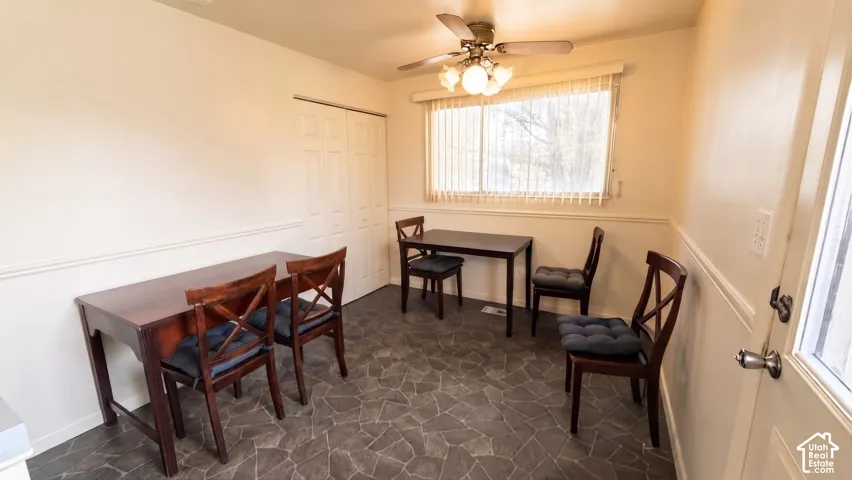 Multi-functional room featuring stone-patterned vinyl flooring, dual-panel closet doors, chair rail molding, and a ceiling-mounted light fixture with a fan