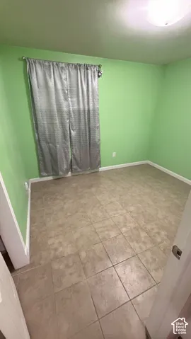 Interior space featuring neutral-toned tile flooring, light-colored wall surfaces, and a ceiling-mounted light fixture