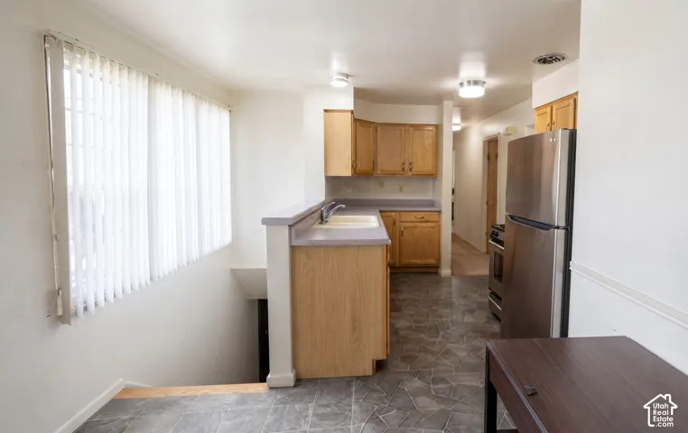 Kitchen featuring wood cabinetry, stone-finish countertops, stainless steel refrigerator, and tile flooring