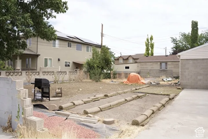 Spacious backyard featuring a concrete patio, partial sod installation, and established trees