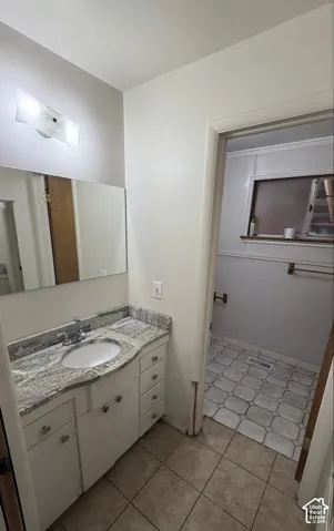Bathroom vanity featuring a speckled countertop with an integrated sink, white cabinetry with storage drawers and cabinet doors, and a chrome faucet