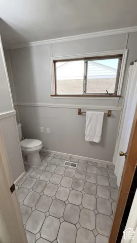 Bathroom featuring geometric tile flooring, chair rail molding, and a horizontal sliding window