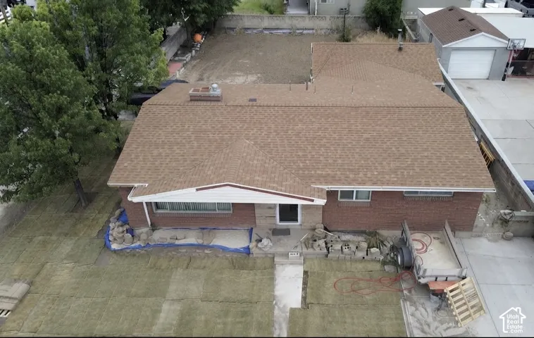 Single-story brick residence with an attached garage featuring a brown shingle roof