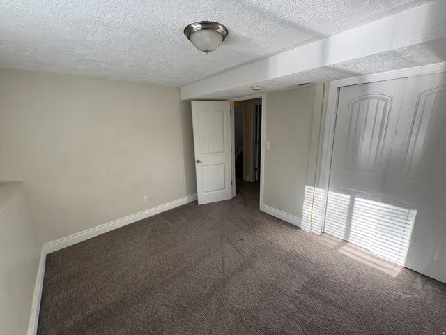 Carpeted room featuring neutral wall paint, white trim, a flush-mount light fixture, and white bi-fold closet doors