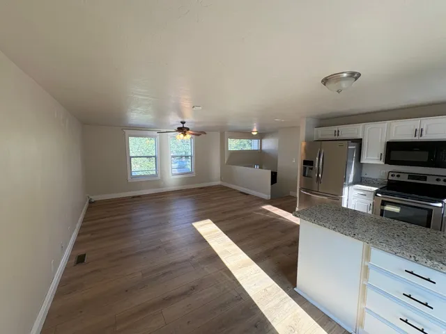 Open-concept living area featuring wood-finish flooring, white baseboards, and neutral wall tones