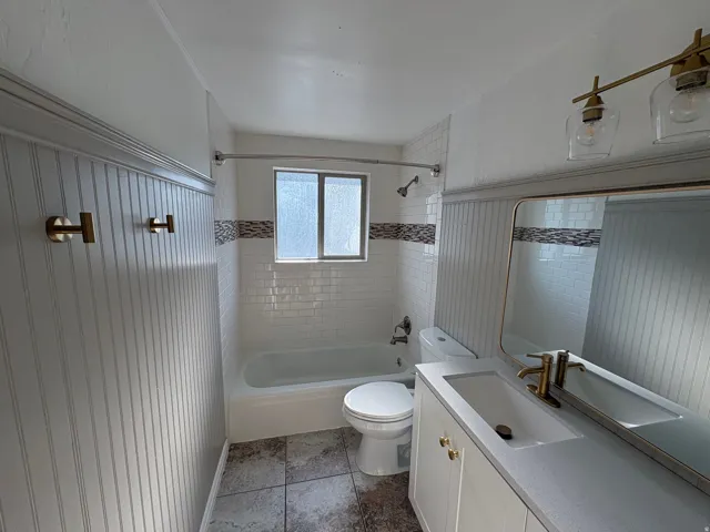 Bathroom featuring a vanity with an integrated sink, a rectangular mirror, and a two-light vanity fixture