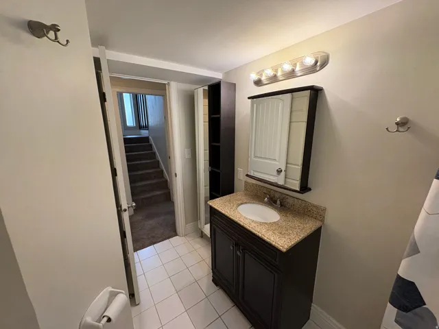 Bathroom featuring a dark wood-finish vanity with a granite countertop, undermount sink, and wall-mounted medicine cabinet