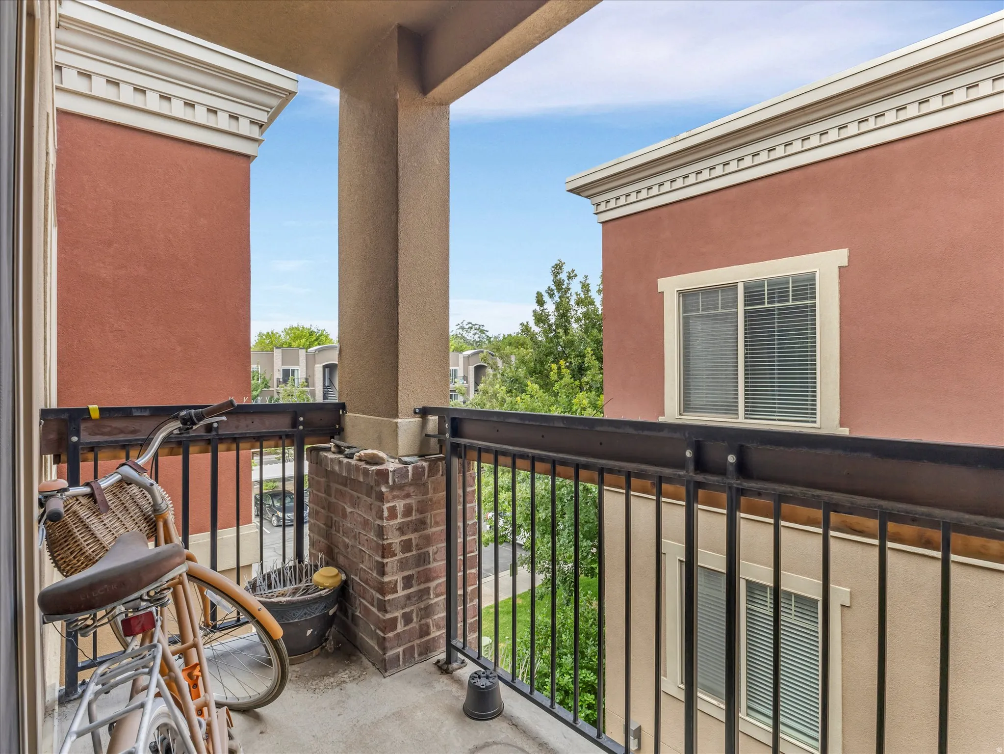Private balcony featuring a concrete floor, black metal railing, and a brick-finish half-wall