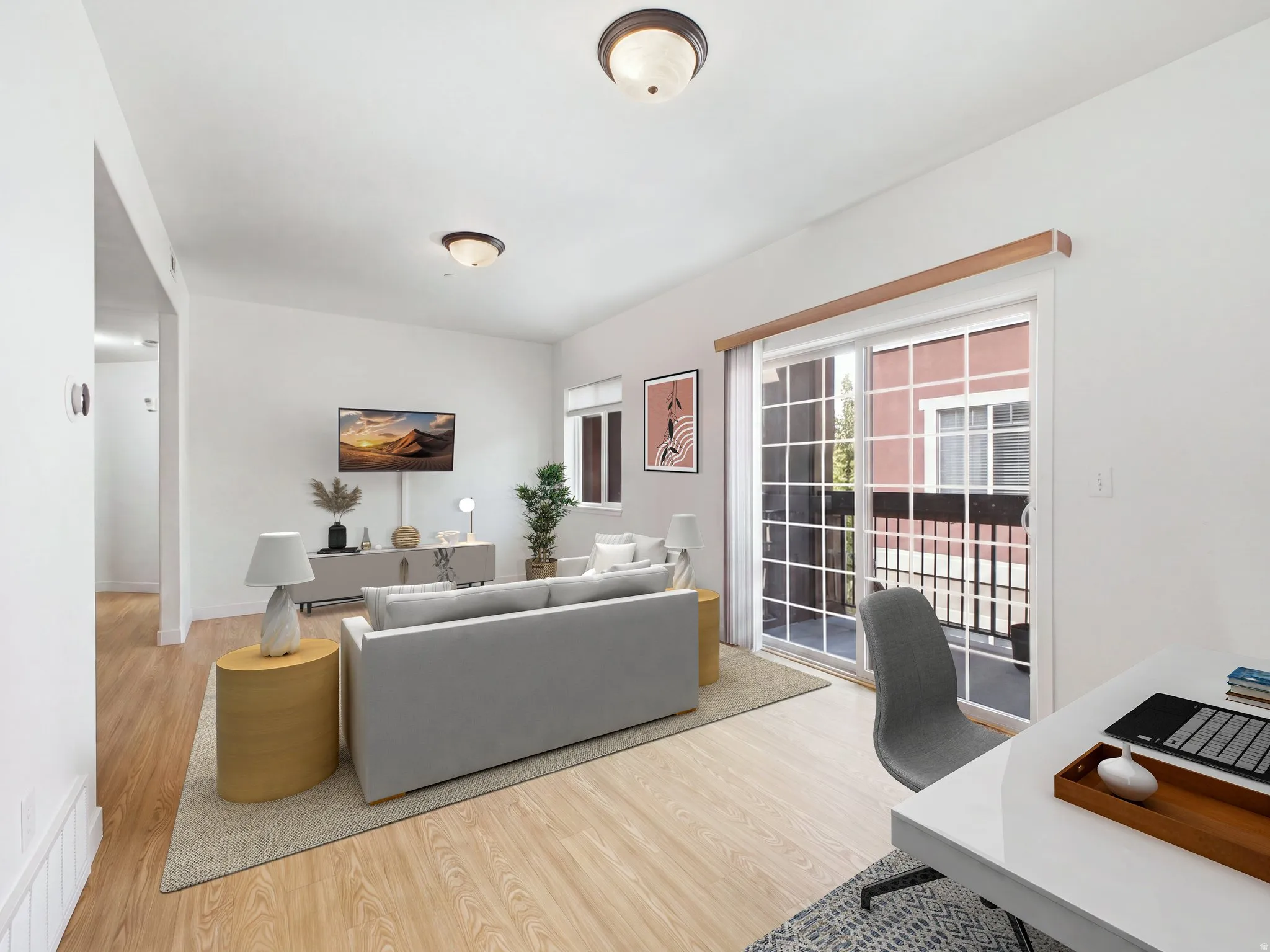 Spacious living area featuring wood-finish flooring, white walls, and two ceiling-mounted light fixtures