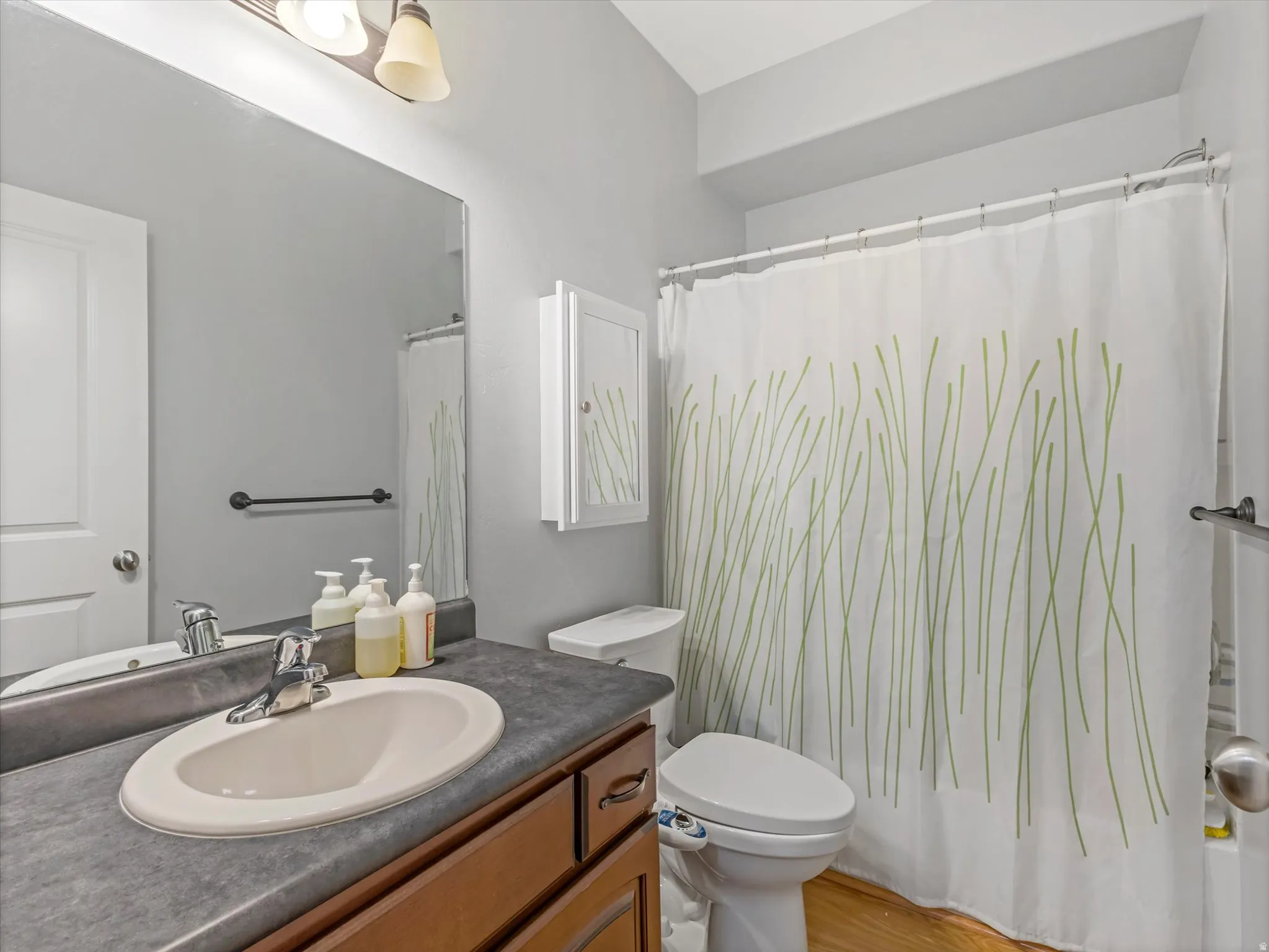 Bathroom featuring a wood-finish vanity with an integrated sink and laminate countertop