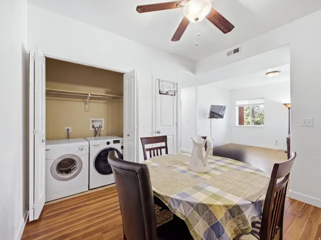 In-unit laundry with washer and dryer included, wood-finish flooring, white walls, and a recessed ceiling fan with integrated lighting