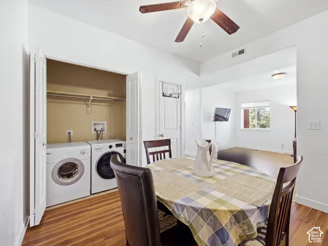 In-unit laundry with washer and dryer included, wood-finish flooring, white walls, and a recessed ceiling fan with integrated lighting