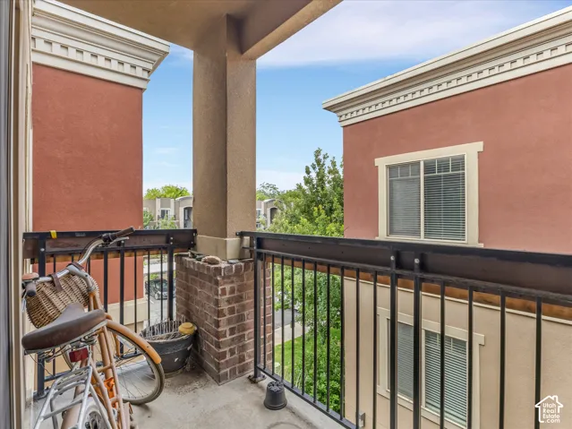 Private balcony featuring a concrete floor, black metal railing, and a brick-finish half-wall