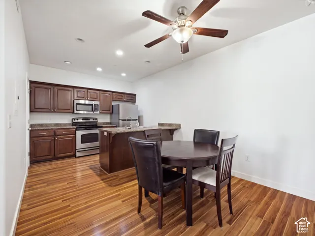 Hardwood flooring, dark wood cabinetry, stainless steel appliances, recessed lighting, and a ceiling fan with light fixture