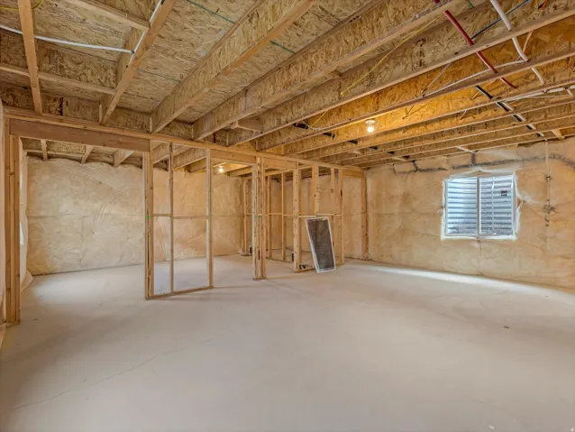 Unfinished basement featuring exposed wood joists, framed interior walls, and a concrete floor