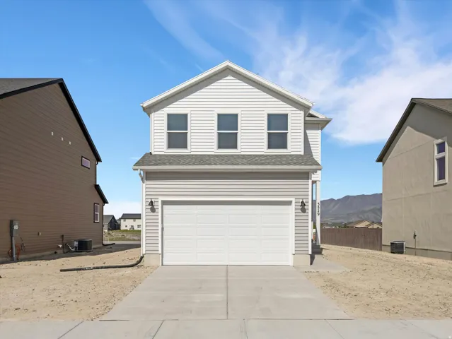Two-story residence featuring light gray siding, white trim, and a two-car garage