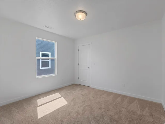 Light-filled interior space featuring neutral tone carpeting and a single window with white trim