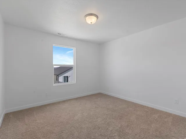 Bright interior space featuring a window with natural light, light-toned carpeting, white walls, and a flush-mount ceiling light