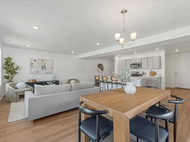 Open-concept living space featuring wood-finish flooring, recessed lighting, and a modern chandelier