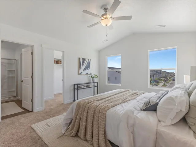 Vaulted ceiling bedroom featuring carpeting, two windows, and an overhead ceiling fan with lighting