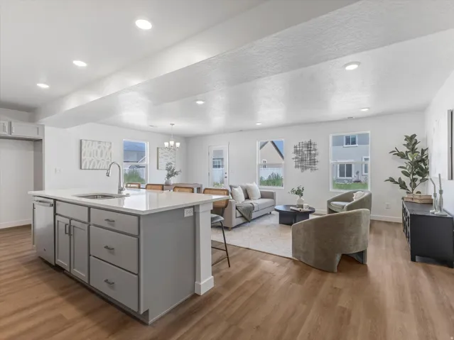 Contemporary kitchen island featuring light gray cabinetry, a stainless steel sink with a gooseneck faucet, and a light-toned countertop