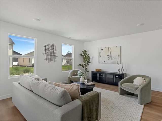 Living area featuring wood-finish flooring, white walls, multiple windows providing natural light, and recessed ceiling lighting