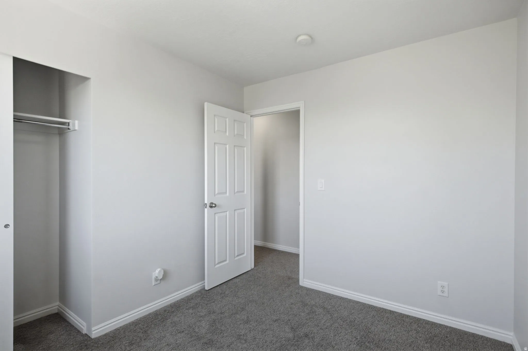 Light gray walls with white trim and a neutral gray carpet
