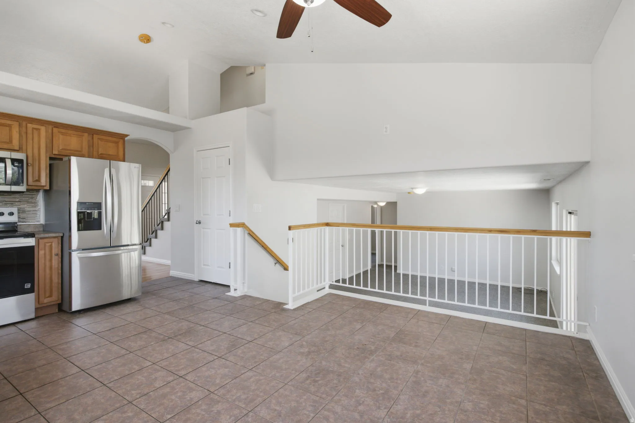 Open concept living area with tiled flooring, vaulted ceilings, and a ceiling fan