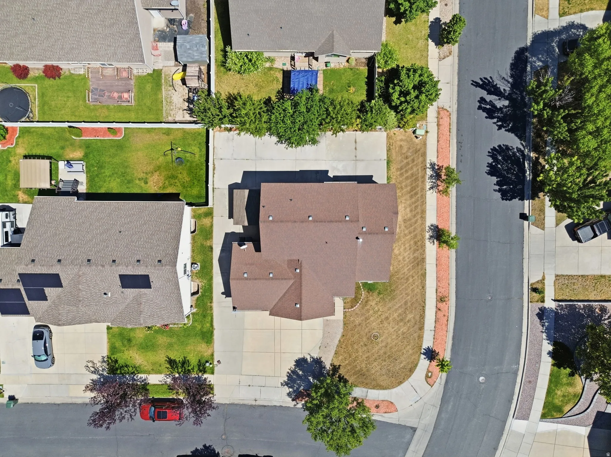 Single-family residence with a brown shingle roof, concrete driveway, and established trees