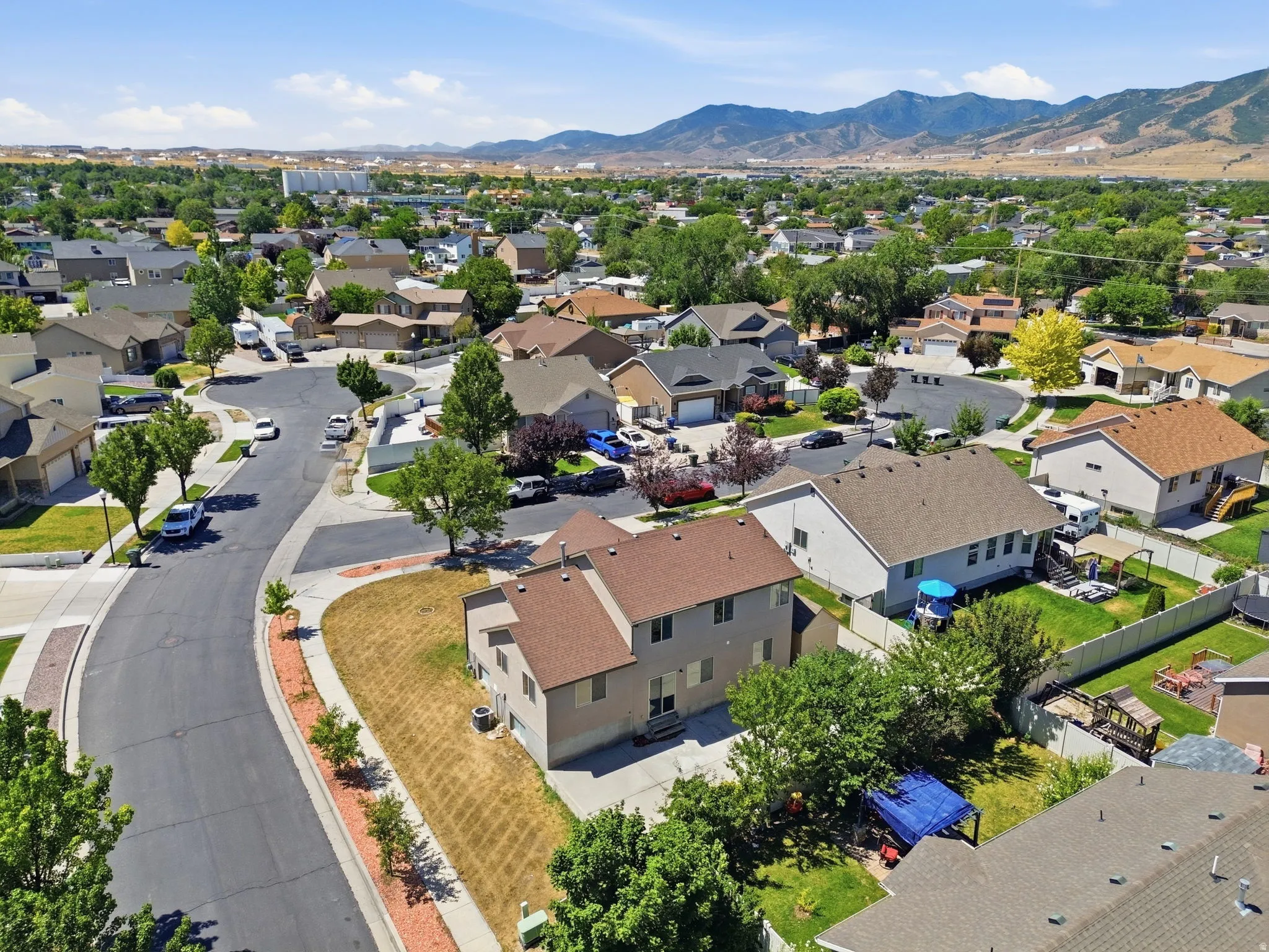 Residential area featuring a cul-de-sac street, mature trees, and a distant mountain range