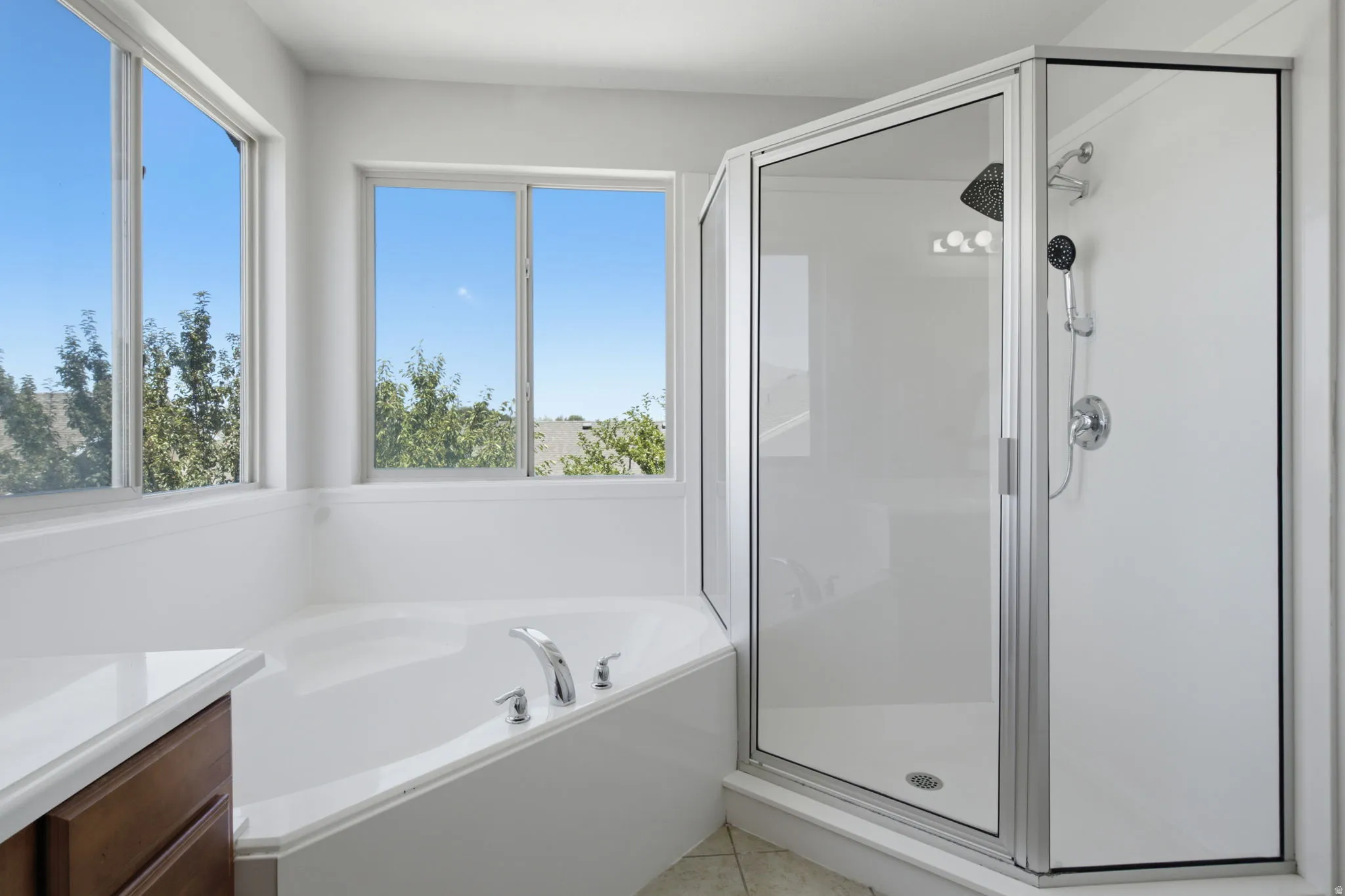 Corner soaking tub with chrome fixtures and surrounding windows