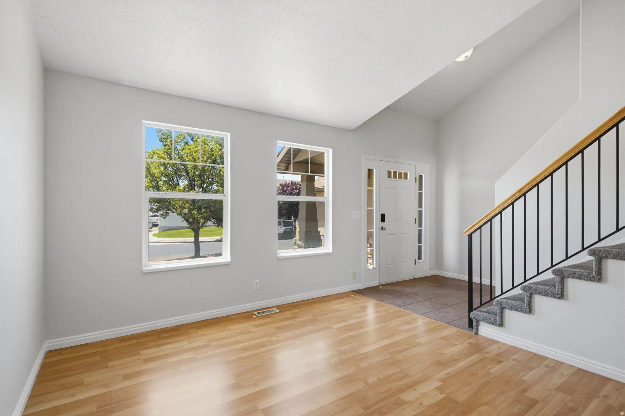 Bright entry space featuring wood-finish flooring, a two-story ceiling, and white trim throughout