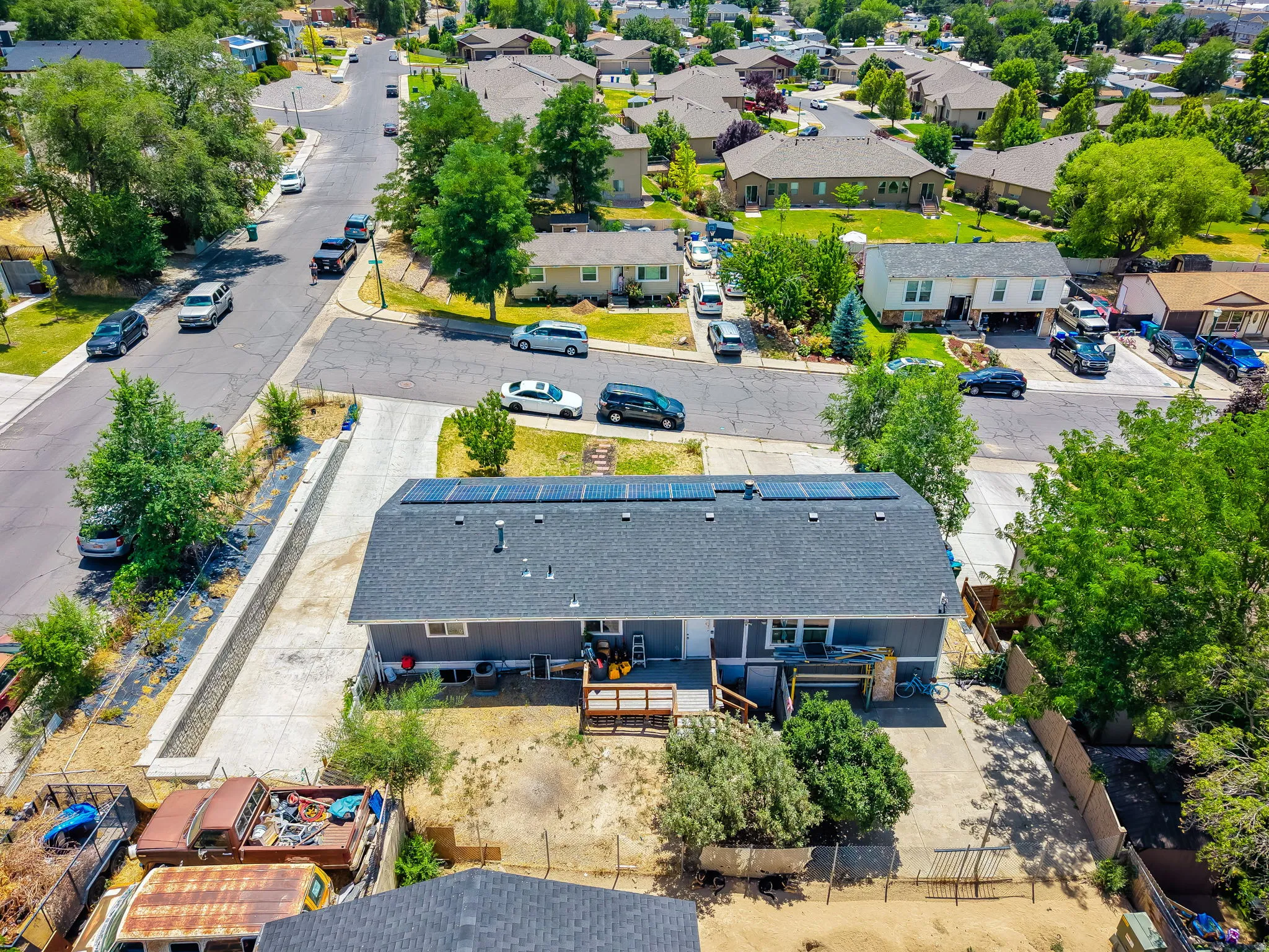 Single-family residence featuring a gray exterior, dark shingle roof with solar panels, and a concrete driveway