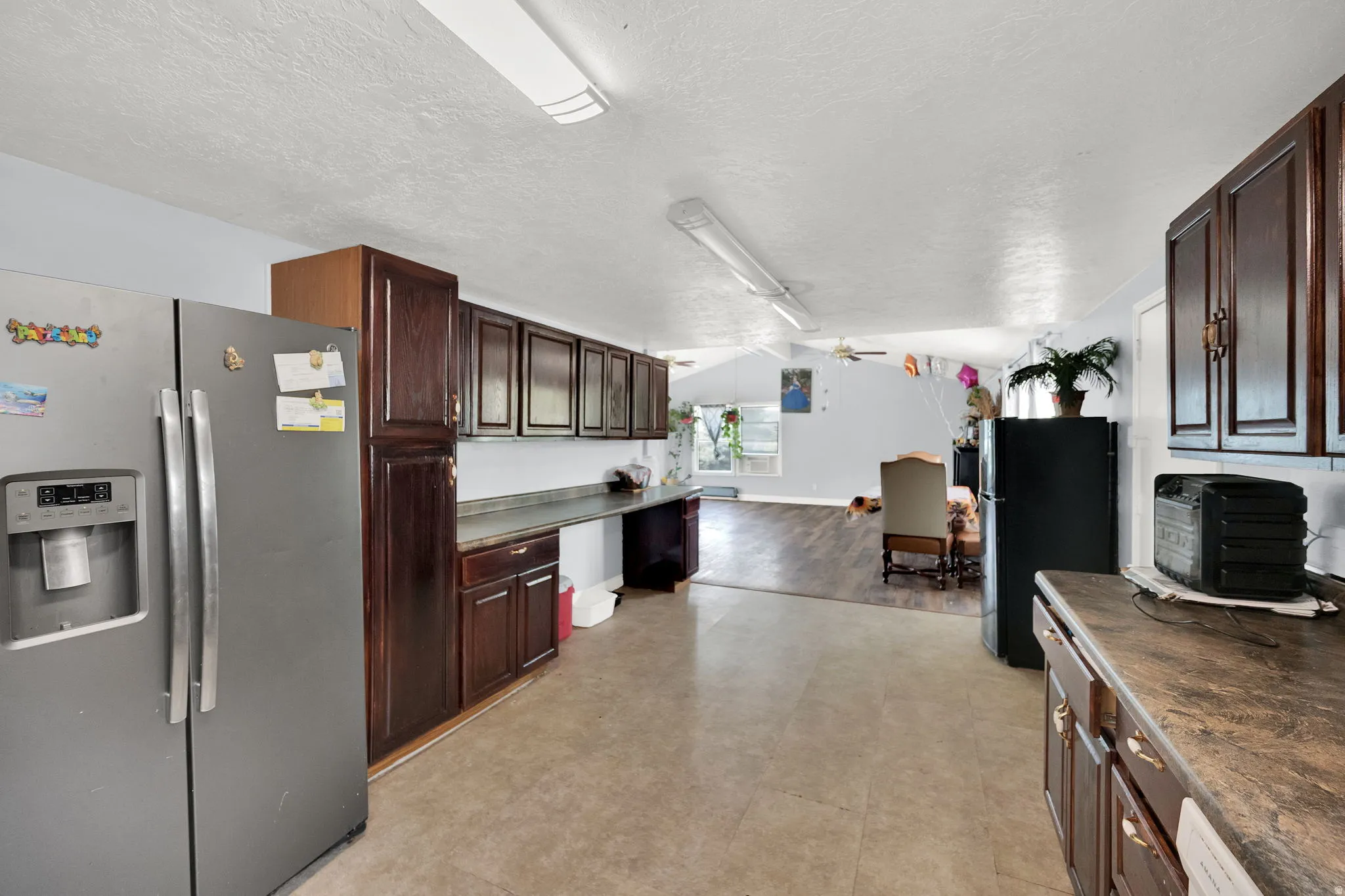 Kitchen featuring dark wood-finish cabinetry, a stainless steel refrigerator, and ample counter space