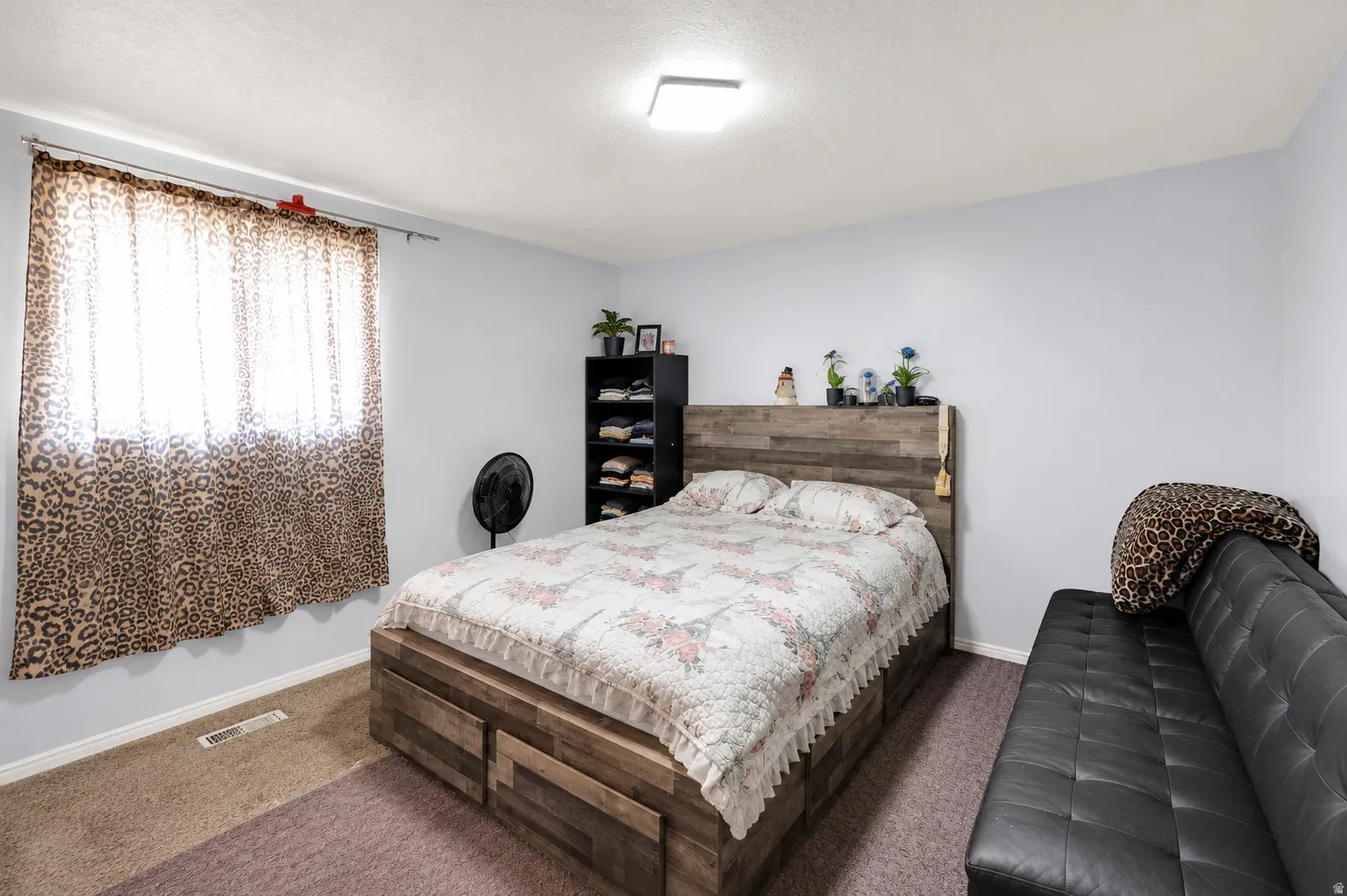 Spacious room with a window, ceiling-mounted light fixture, light gray walls, and carpet flooring