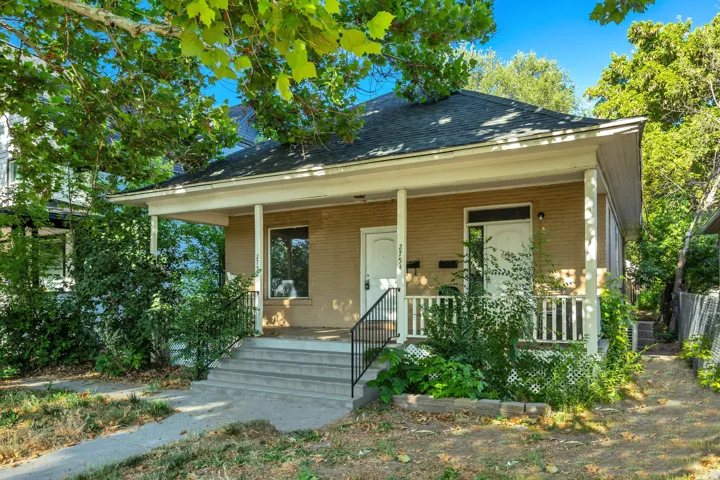 Brick exterior with covered front porch, concrete steps, white railings, and white entry doors
