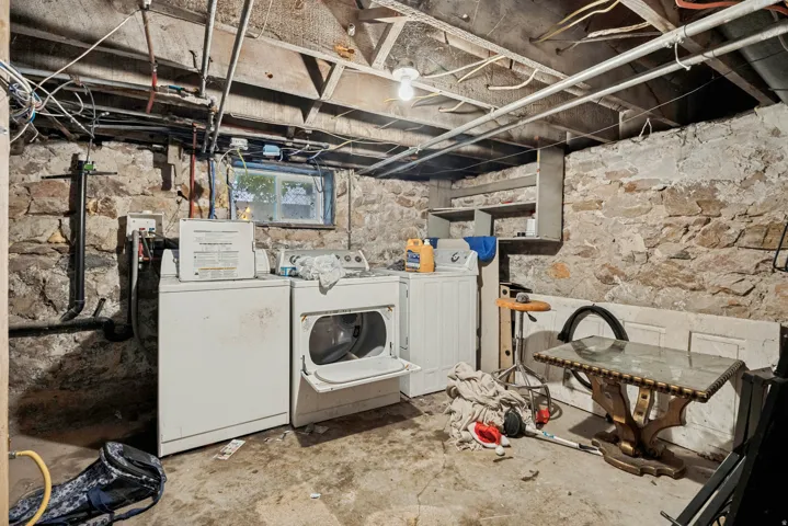 Basement space featuring exposed stone walls and a utility window