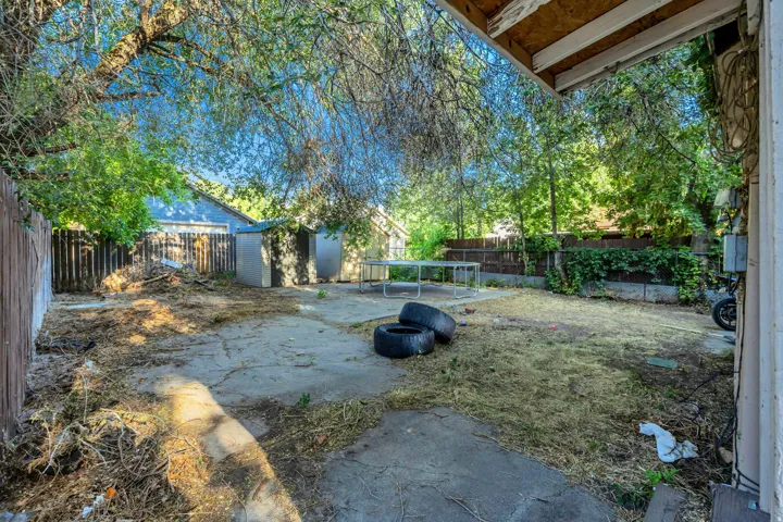 Expansive outdoor space featuring mature trees, a privacy fence, and concrete patio areas