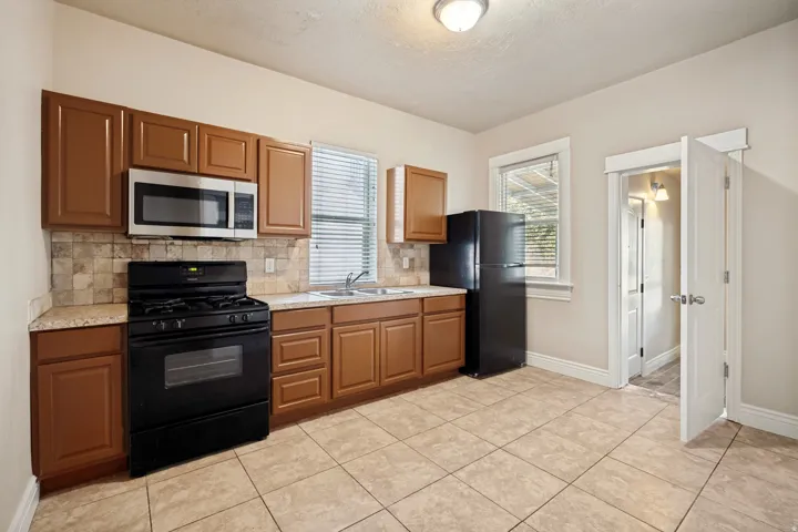 Kitchen featuring warm-toned cabinetry, light-toned countertops, and a tiled backsplash