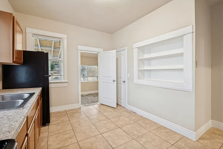 Kitchen featuring tile flooring, wood-finish cabinetry, laminate countertops, and a double basin stainless steel sink