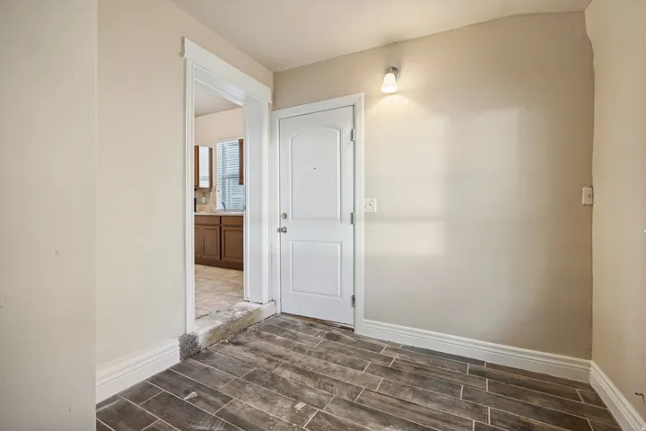 Entryway featuring wood-look tile flooring, crisp white trim, and a wall-mounted sconce