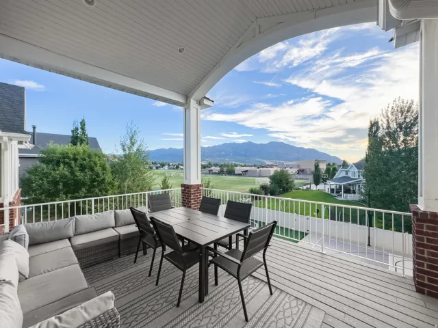 Covered outdoor deck featuring white plank flooring, brick pillars, and white railing