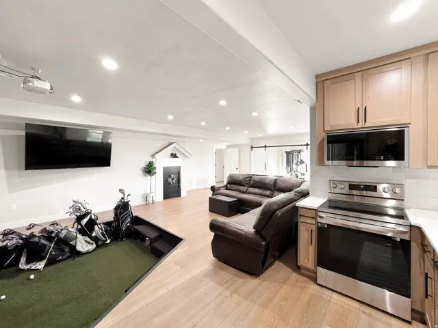 Open-concept entertainment space featuring wood-finish flooring, recessed lighting, and a built-in putting green